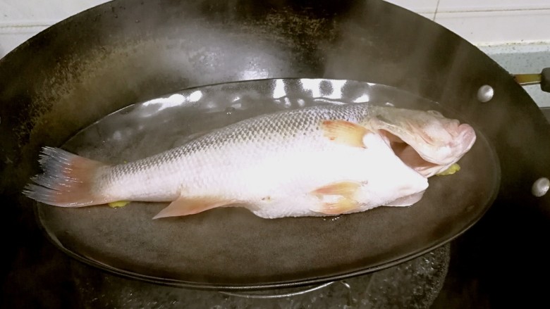 粤式清蒸鲈鱼,锅里烧开水，放入鲈鱼，盖盖子蒸7分钟。