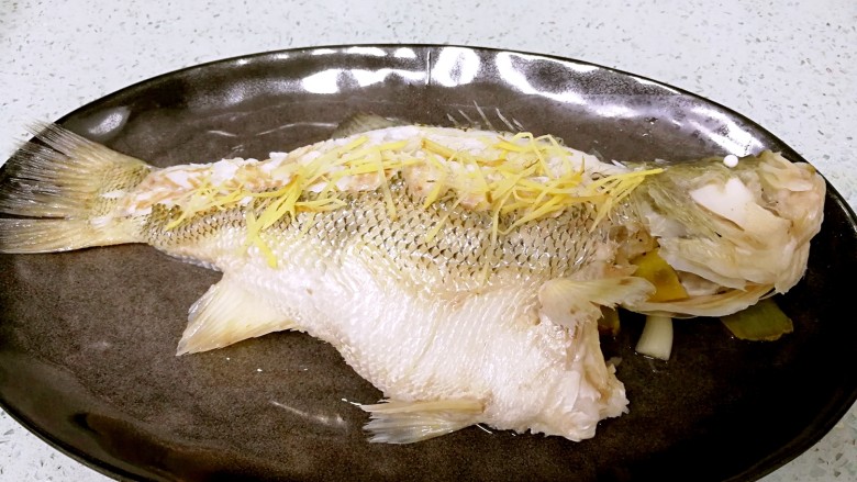 粤式清蒸鲈鱼,鱼蒸好后取出，倒去盘内浮水，摆上姜丝。