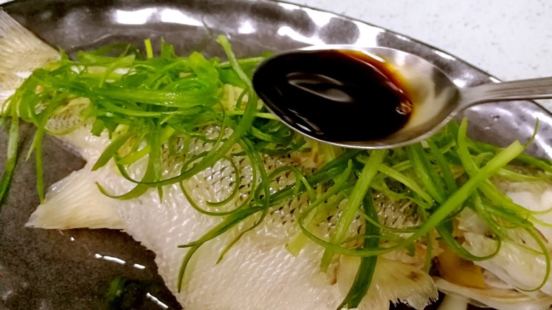 粤式清蒸鲈鱼,往鱼身上均匀地淋浇3勺生抽。