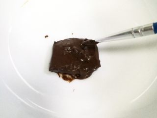hellokitty饼干,取一小块黑色巧克力放碗中，放微波炉中加热至融化，也可以隔温水至融化。