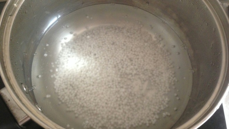 牛奶芒果西米露,先煮西米。锅里的水烧开后，放入西米搅拌。水再次煮开后，盖上盖子，焖十分钟。