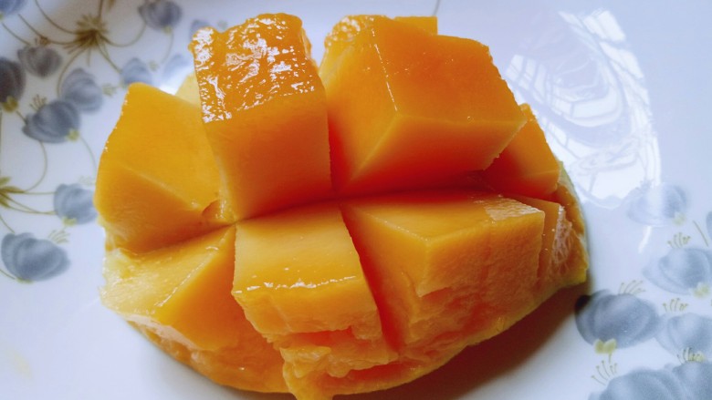 芒果千层蛋糕,芒果从中间切开，在一半的芒果肉上划十字刀，再小心用水果刀把果肉切下来。