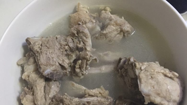 正宗东北酸菜炖大骨头,将煮脊骨盛在碗中，将锅中上面的汤倒出，留下二分之一倒入盛骨头的碗中。