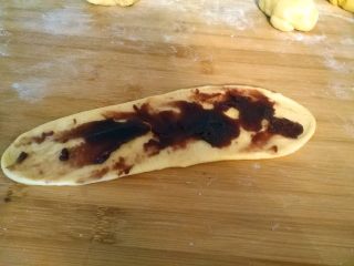   红豆吐司包,将一个面团，擀成长舌状。然后把红豆沙涂抹在面团表面。