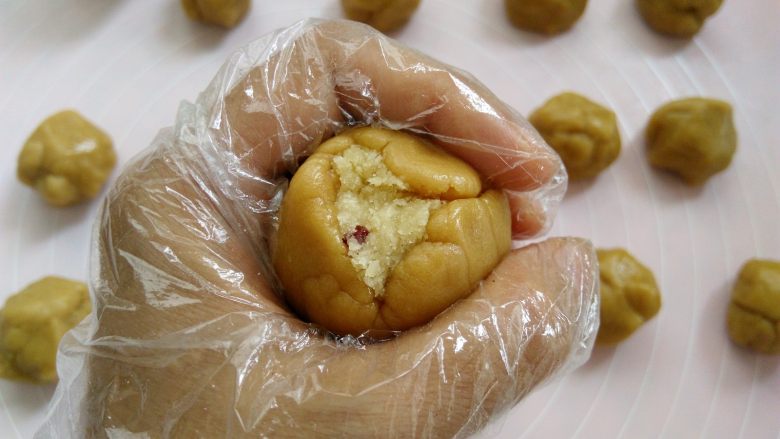 椰蓉蔓越莓月饼,手心合起来，用虎口把面团慢慢收圆，皮厚的地方可以推到皮薄的地方，尽量推的均匀一点