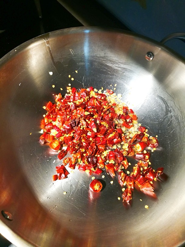 香糍粑耗儿鱼,改小火放入花椒和辣椒段(海椒、二荆条、朝天椒用剪刀剪成小段)用小火煸一到两分钟，超出香味