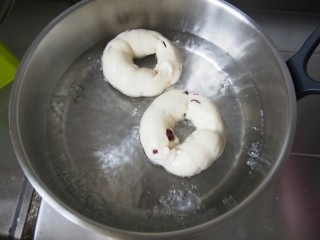 蔓越莓贝果,糖水煮开后转小火，将发酵好的贝果放入，每面烫30秒左右，捞出控水放入烤盘。烤箱中层上下火180℃20分钟左右即可。