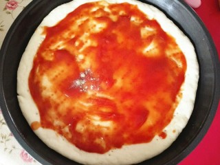 黑胡椒牛肉披萨,中间涂上蕃茄酱，并撒上适量黑胡椒，涂抹均匀，边缘图上蛋液