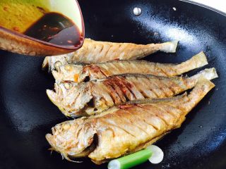 手把手教你做 家熬黄花鱼,放入煎好的鱼，沿锅边倒入调好的碗汁，迅速盖上锅盖。