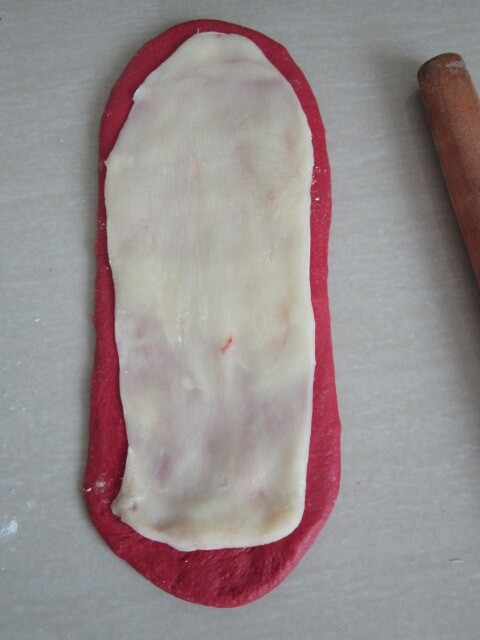 红丝绒麻薯软欧,取一份面团擀成长舌状，铺上麻薯。