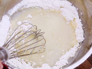古早蛋糕,将面粉倒入加热好的葵花籽油内，搅拌均匀。