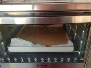 淋面可可蛋糕,将拌好的蛋糕糊倒入到铺了油纸的正方形烤盘里，放入已经提前预热到175度的烤箱下层，烘烤18分钟。