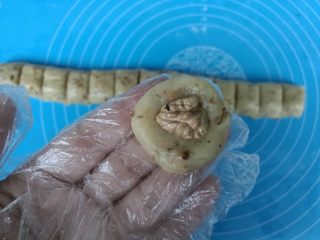 植物油版核桃酥,取一个小剂子揉圆，用大拇指按扁，中间放一颗核桃仁。