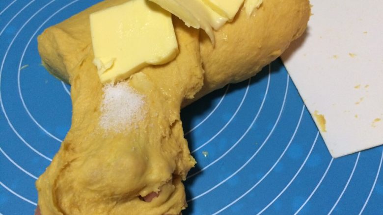 南瓜蜜豆肉松包,把面团揉至初步扩展，能拉出厚厚的膜，用手撑开非常容易破的状态，加入黄油与细盐揉进面团中。