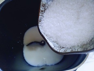 蜜豆小面包,首先将牛奶倒入面包桶，再加入白砂糖。