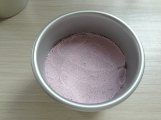 紫薯松糕,4寸活底模底部垫一张油纸，内壁抹一层油。放入一半的糕粉，用汤匙轻轻刮平表面，切记不要震动和按压。