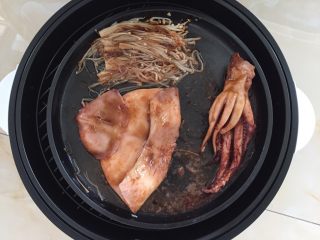 香烤鱿鱼,10分钟后，鱿鱼受热卷起，没关系，准备少许烤肉酱，均匀涂抹于鱿鱼和金针菇上