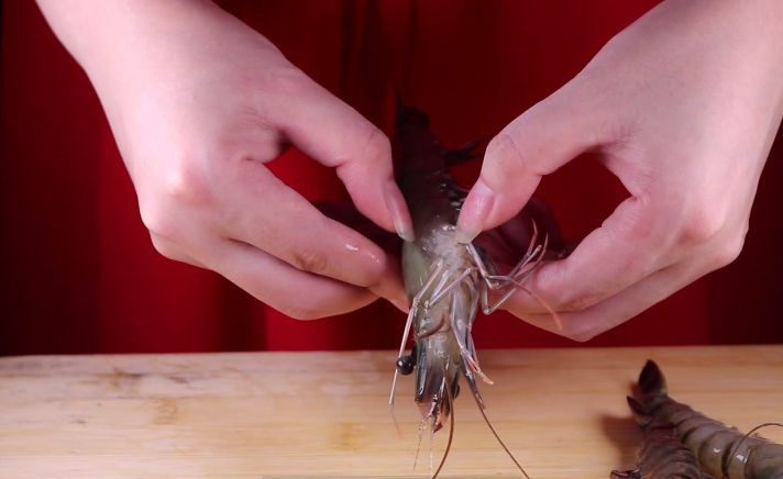 往虾里打入一颗蛋——虾扯蛋,接着我们开始剥虾壳，把虾头的部分剪掉，从虾的肚子处开始剥壳，也可以将虾放入冰箱里速冻，取出来带有点冰沙在虾的表面即可，这样葱虾尾一拉，就能很