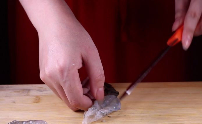往虾里打入一颗蛋——虾扯蛋,接着用刀子给虾仁开背备用。