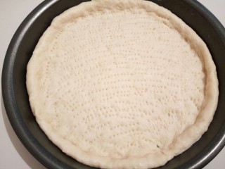 自制火腿肠披萨,醒发好的面皮擀圆（轻轻擀，不然面皮压太紧了，口感不好，）披萨盘刷一点黄油（出锅的时候，好拿一点）把擀好的面皮，移到披萨盘，整形，四周稍微厚一点，再用叉子，轻轻戳，（防止烤的时候鼓起来）然后放烤箱，200度，中层，先烤5分钟（也可以直接烤，）