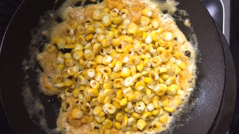 金沙玉米,倒入玉米，翻炒均匀，使每颗玉米粒都包裹上金灿灿的咸蛋黄沙，再根据自家口味适量加一点点盐后即可出锅。
