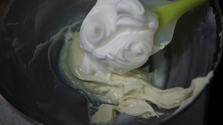 只用蛋清的美味烘焙 | 酸奶溶豆,挖取三分之一蛋白霜，到酸奶糊中，拌匀。速度要快，简单拌三五次就可以了。
