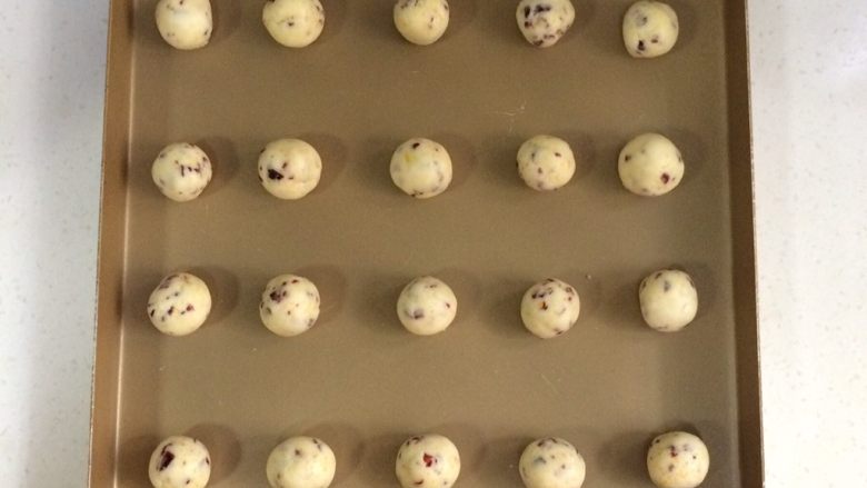 蔓越莓玛格丽特,冷藏后取出饼干面团，分成20等份，用双手搓成圆球状，一一摆入烤盘内。