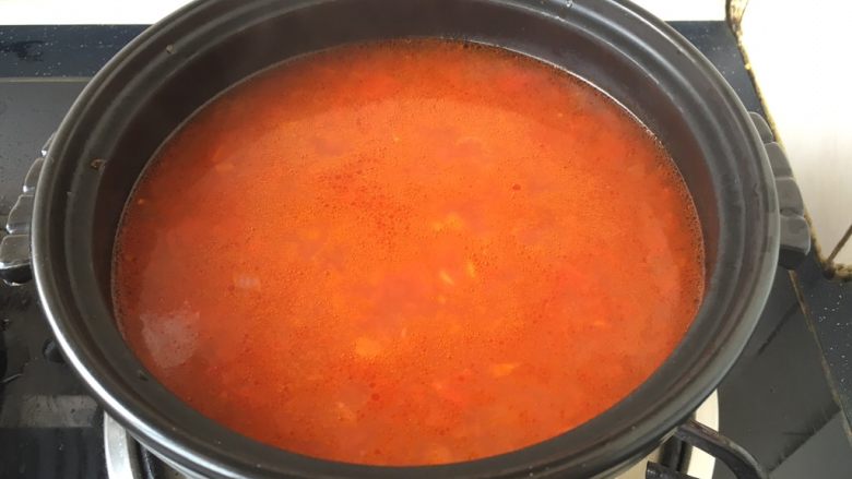 番茄金针菇肥牛,取一个砂锅，放在炉灶上开大火，在砂锅里放入适量的番茄汤。
