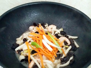 鲜虾菌菇面,放入胡萝卜丝，剩余的葱段，生抽炒至断生。