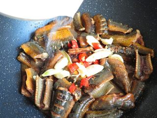 红烧鳝鱼,将炸过的姜、蒜、红辣椒倒入锅内，加一碗水盖上锅盖烧5分钟