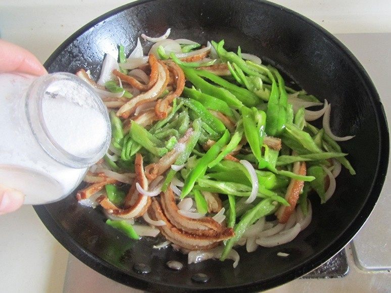 青椒洋葱炒牛肚丝,青椒丝翻炒变色后加入适量的盐调味， 翻炒均匀即可盛入盘中。