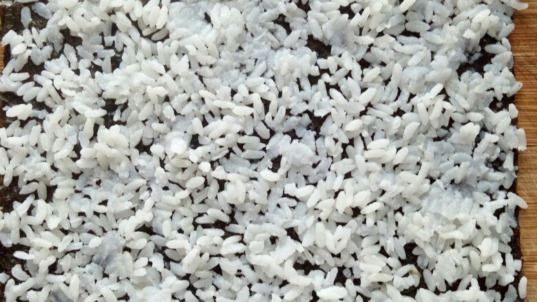 培根寿司卷,把米饭均匀展开，尽量薄，因为太多吃两个就饱了。注意四边要铺上米饭不能空。