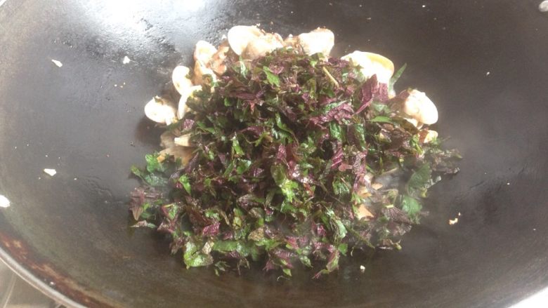 紫苏炒花甲,加入紫苏叶碎翻炒，盖锅盖煮1分钟左右