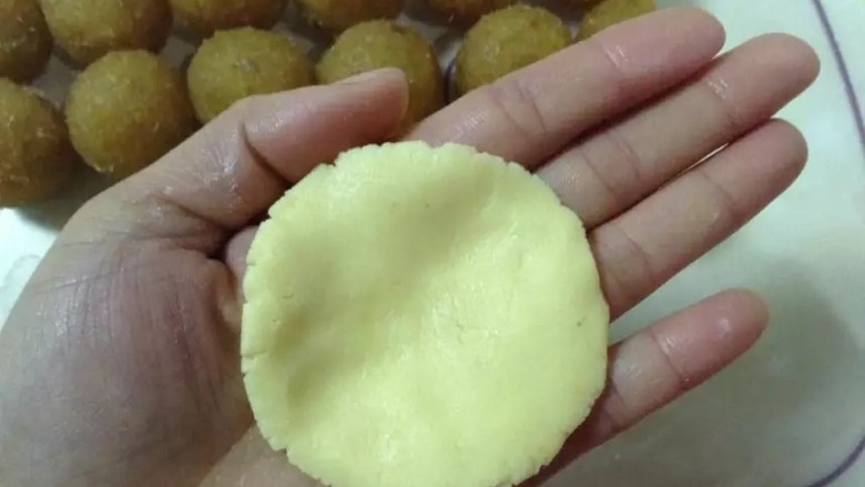 凤梨酥自己动手做真材实料皮薄大馅。,取一块称好的酥皮面团，揉成圆形。用手把面团压扁.