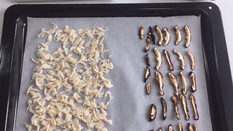 宝宝辅食：香菇虾皮粉,烤盘放上烘焙纸，把虾皮和香菇条均匀的码在上面