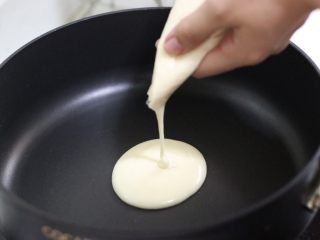 奶香四溢的酸奶厚松饼,锅子小火预热，剪一个口子，从中心圆点，挤进适量面糊