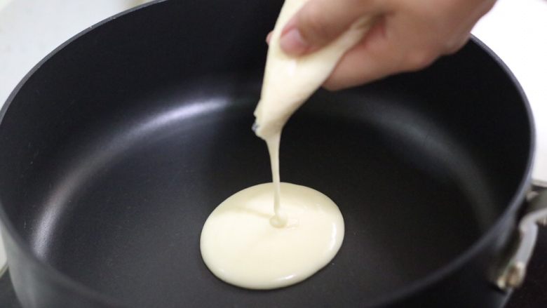 奶香四溢的酸奶厚松饼,锅子小火预热，剪一个口子，从中心圆点，挤进适量面糊