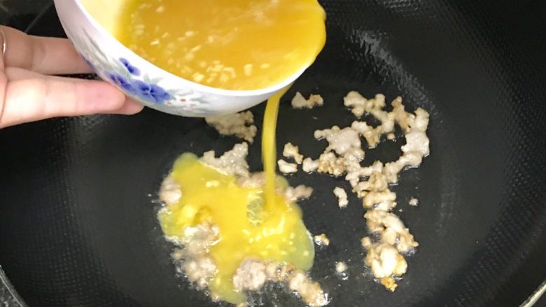 碎肉鸡蛋饼,把碎肉铺整齐后，就把混合好的蛋液均匀地倒入锅中，同时把火关小一些