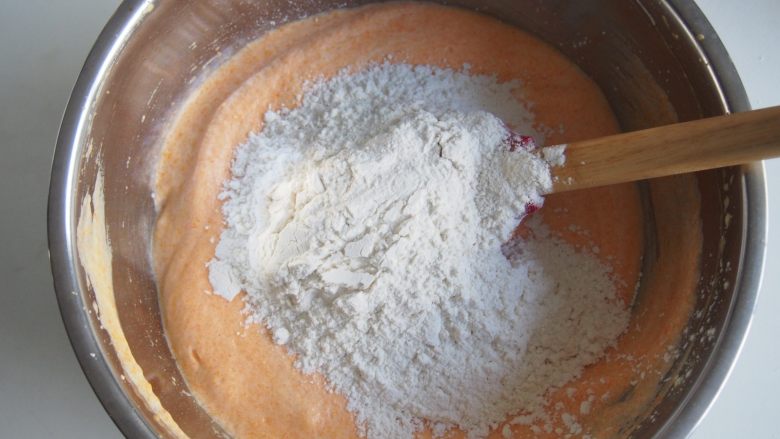 胡萝卜小蛋糕,将面粉过筛后加入蛋黄糊中，切拌均匀。