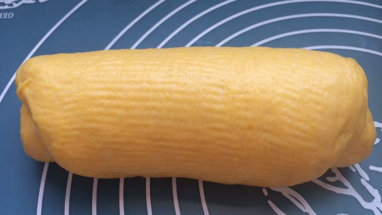 中种南瓜吐司面包,每个面团擀成椭圆形，翻面，轻轻按掉小气泡，卷起，收口向下，盖保鲜膜静置一刻钟。如果面团黏擀面杖擀不开，可以在面团表面抹少量软化黄油。