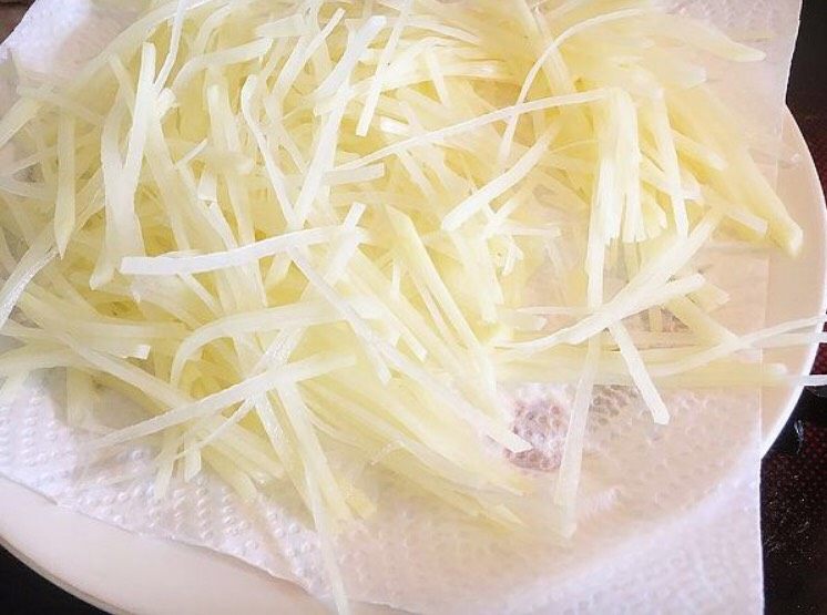 锦绣金丝虾球,泡过水的土豆丝放厨房纸巾上吸干水分。