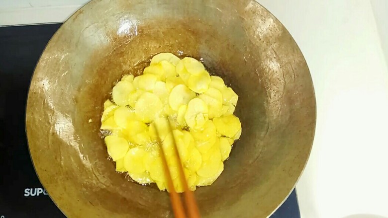 自制薯片,炸制期间不时用筷子拌一下，让土豆片均匀受热。
