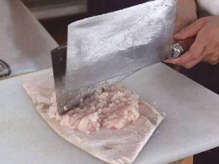 清汤鱼圆,4、将鱼茸放在猪皮上，用刀背剁至变粘。
重点:在猪皮上剁鱼茸时，力度要轻，不能将下面的猪皮剁穿，以免猪肉碎混入鱼茸中。