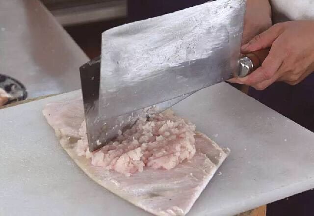 清汤鱼圆,4、将鱼茸放在猪皮上，用刀背剁至变粘。
重点:在猪皮上剁鱼茸时，力度要轻，不能将下面的猪皮剁穿，以免猪肉碎混入鱼茸中。