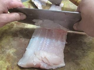 清汤鱼圆,3、用刀从尾部向前一层层刮下鱼茸。
重点:刮取鱼茸时，刀口要放平，刀刃与砧板呈60°夹角，每次只刮下很薄的一层鱼肉泥，这样做可以去净藏在鱼肉中的细碎骨头。