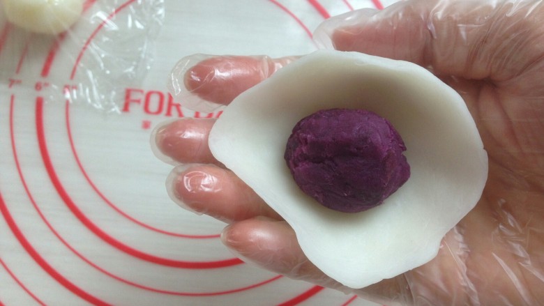 紫薯水晶饼,将饼皮压成圆形放入馅料，用虎口收口。收口处多余的面团揪下来，收口处朝下。