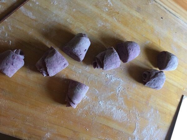 奶香紫薯玫瑰花卷,用刀将卷好的面皮从压痕处切开