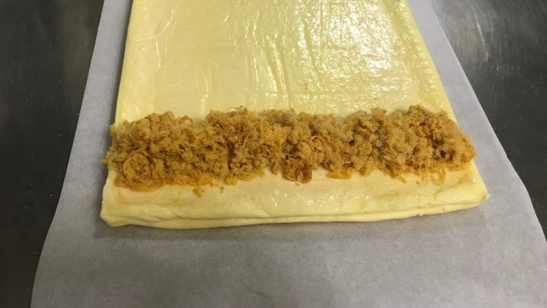 日式棉花肉松蛋糕卷,均匀抹沙拉酱后在顶部放一层肉松后，借助擀面杖卷起