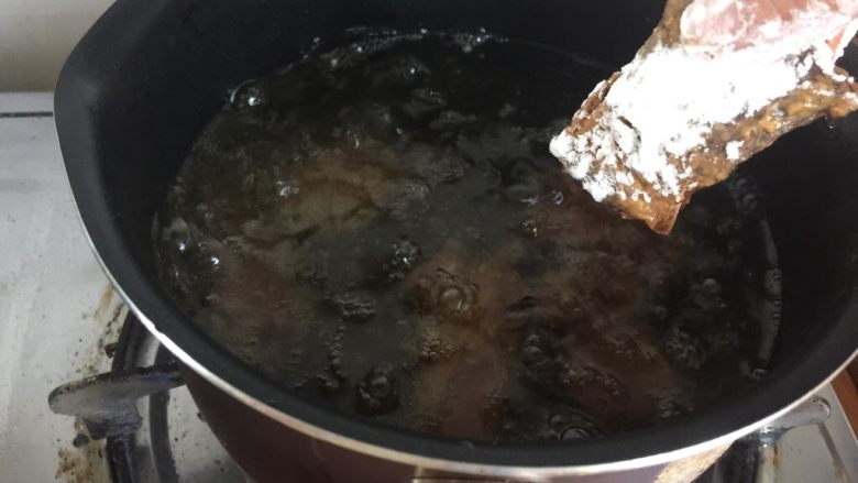 超详细又简单的椒盐排骨,在锅里倒入食用油，中火烧热，将排骨依次放入油炸。