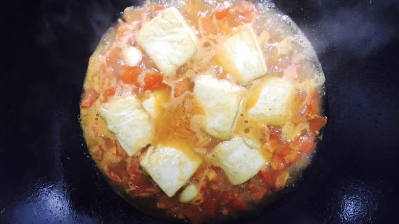 番茄豆腐焖猪肉,倒入豆腐块，铺好，放入适量的盐和糖，用中火焖，记得尝一下汁水的味道是否合适